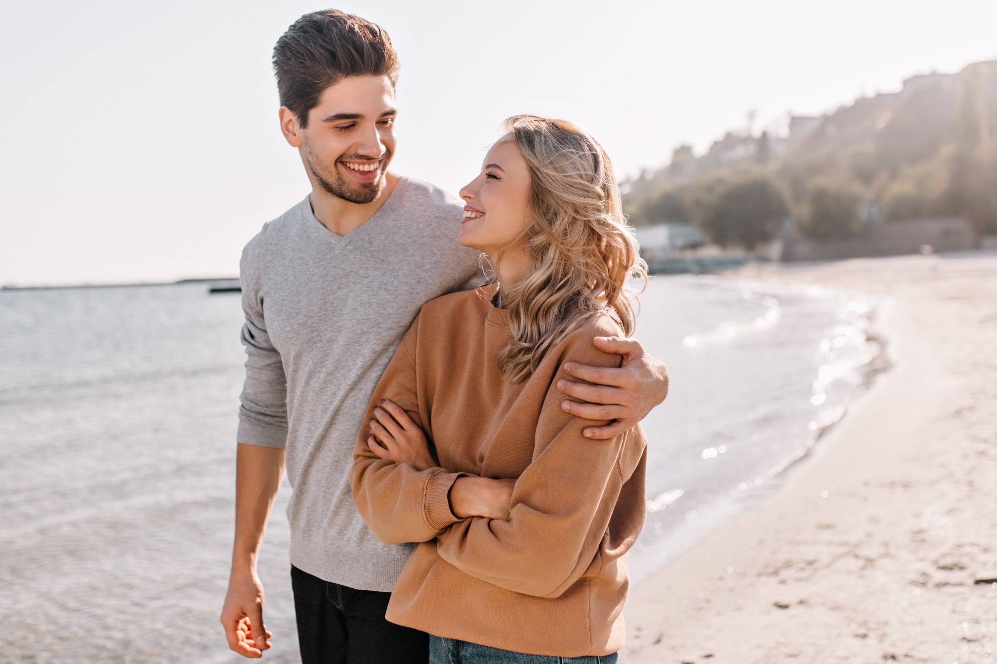 Happy couple walking together on windy beach